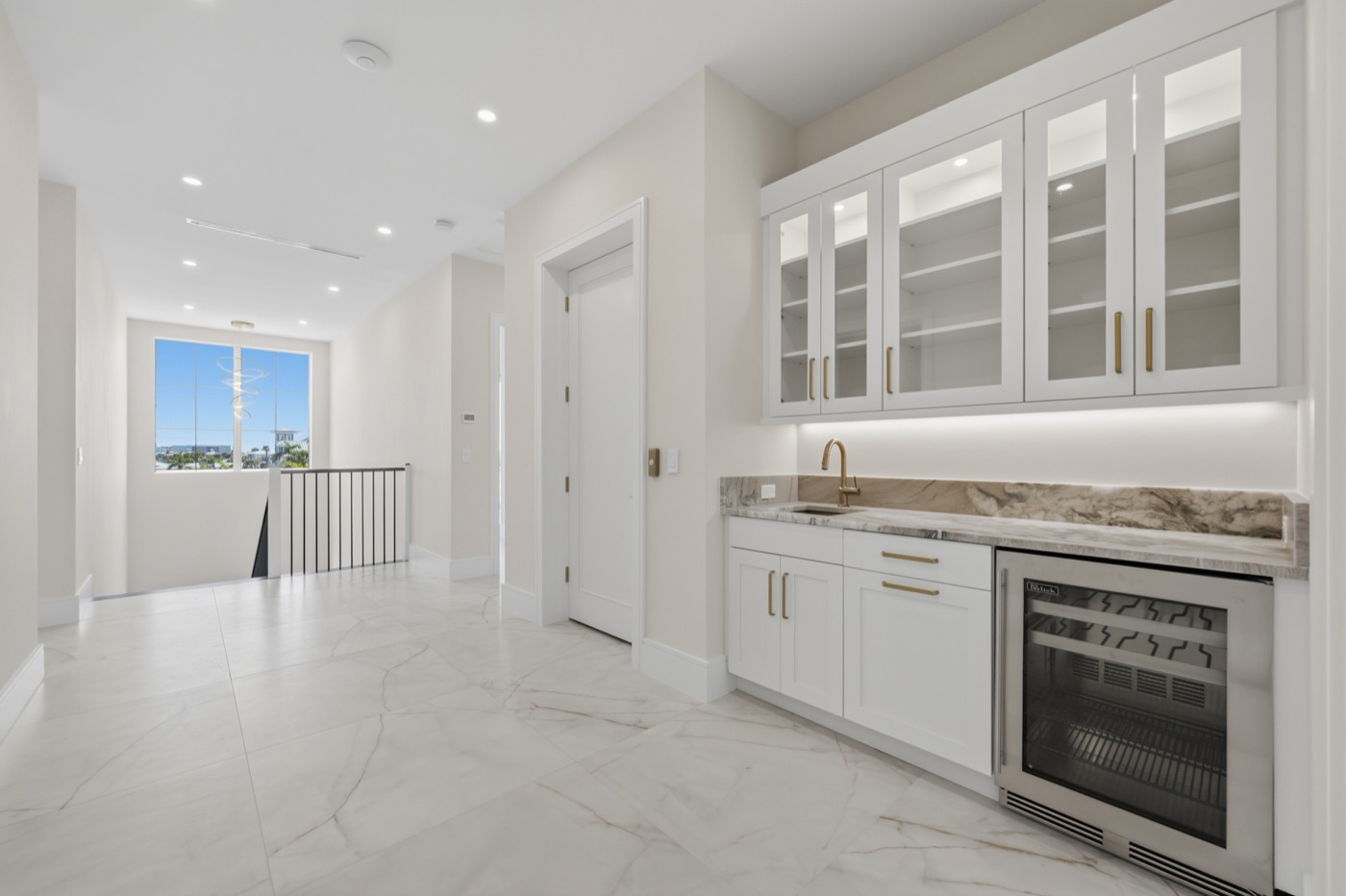 Butler's wet bar with glass-front white shaker uppers, brass pulls and book-matched quartzite — Modern Residence