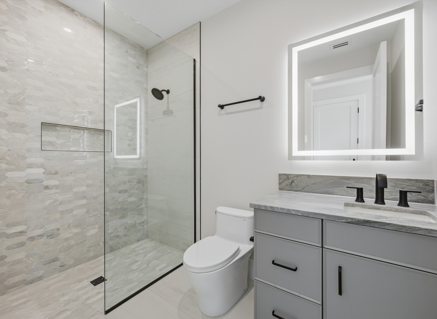 Guest bath with frameless glass shower, hexagon-mosaic feature wall and backlit mirror — Modern Residence