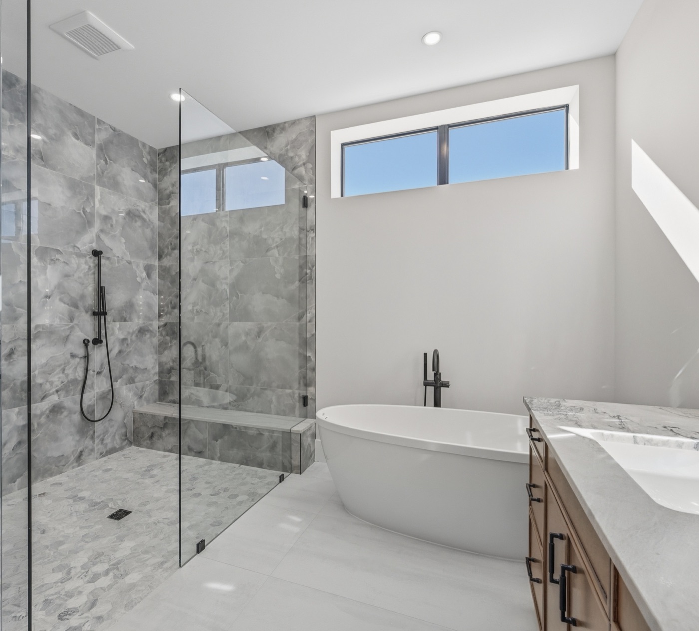 Spa-like primary bath with freestanding sculptural soaking tub and gray-marble shower — Modern Residence