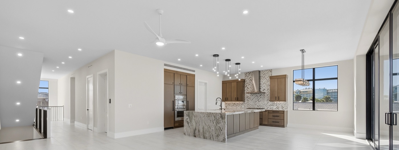 Great-room chef's kitchen with river-veined natural stone waterfall island and white-oak cabinetry — Modern Residence