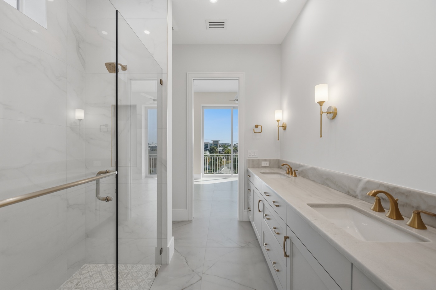 Primary bath with book-matched Calacatta marble walk-in shower and double vanity — Coastal Residence