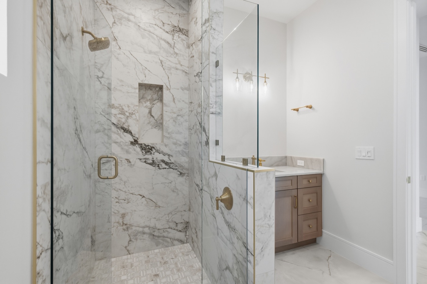 Guest bath with floor-to-ceiling dramatically veined marble shower and brass fixtures — Coastal Residence