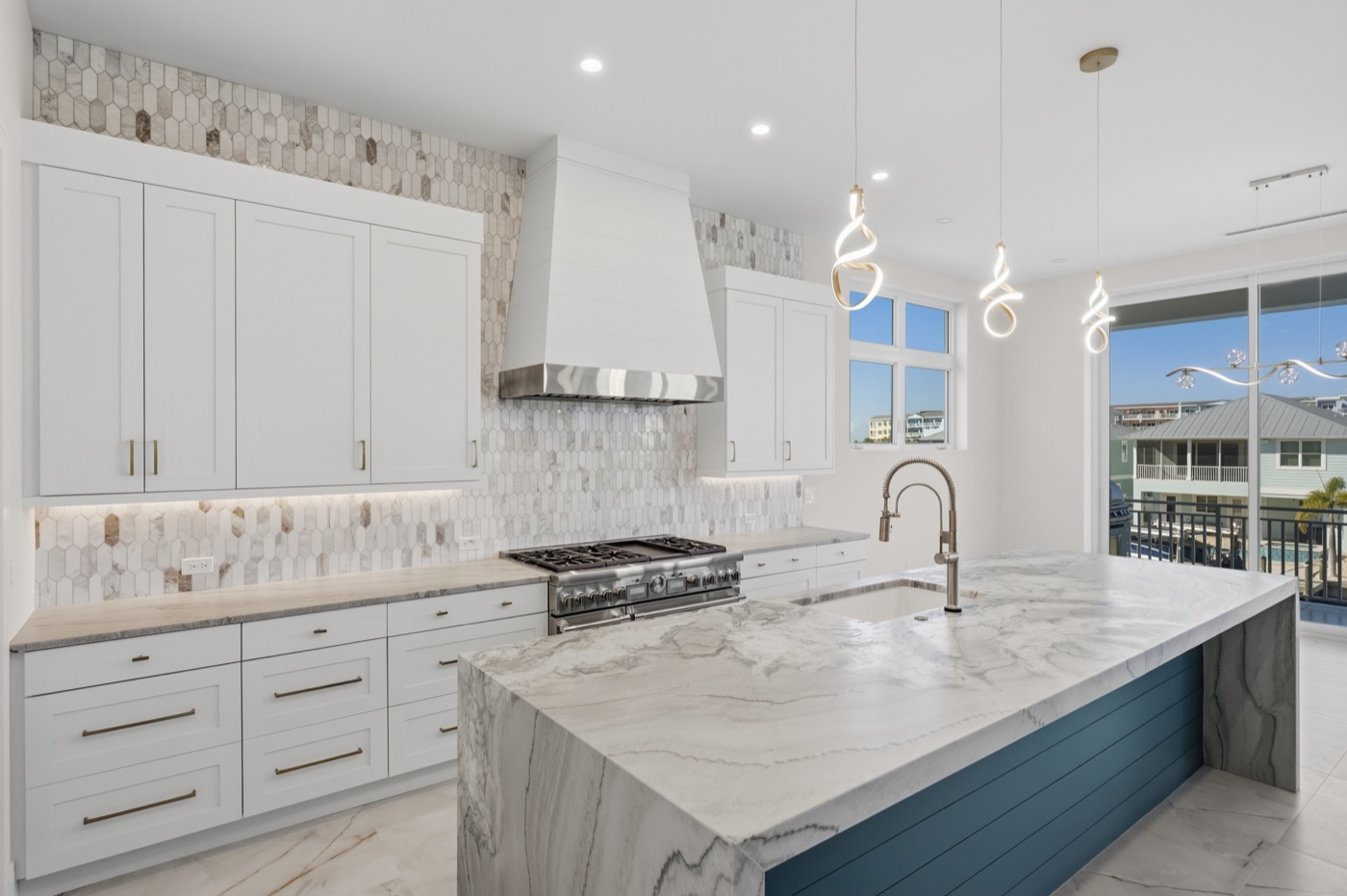Coastal-modern chef's kitchen with book-matched quartzite waterfall island over a navy shiplap base — Coastal Residence