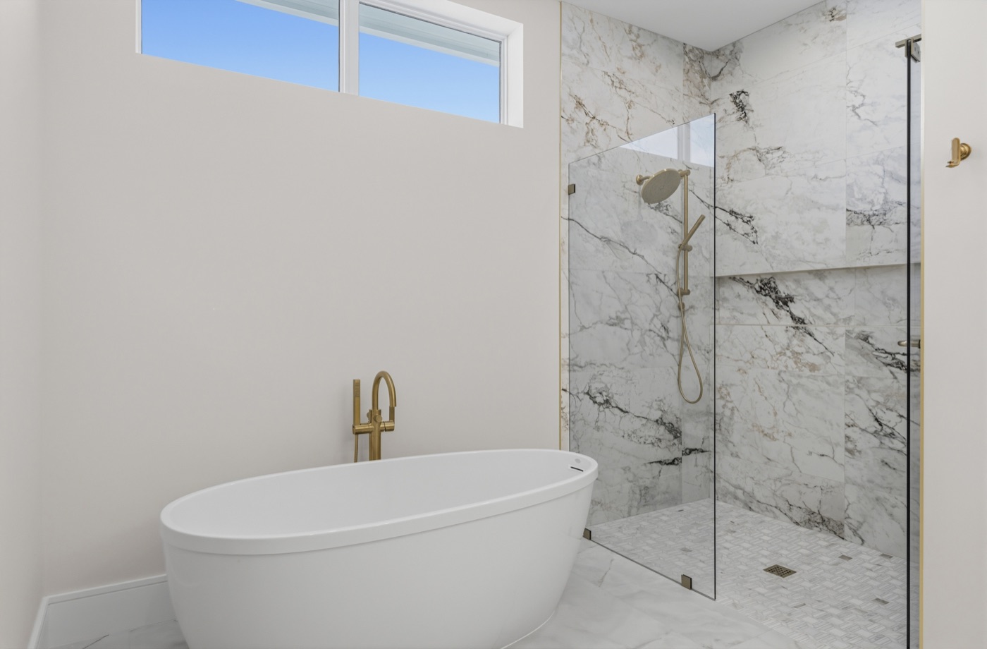 Walk-in marble wet room with sculptural freestanding tub and book-matched slab walls — Coastal Residence