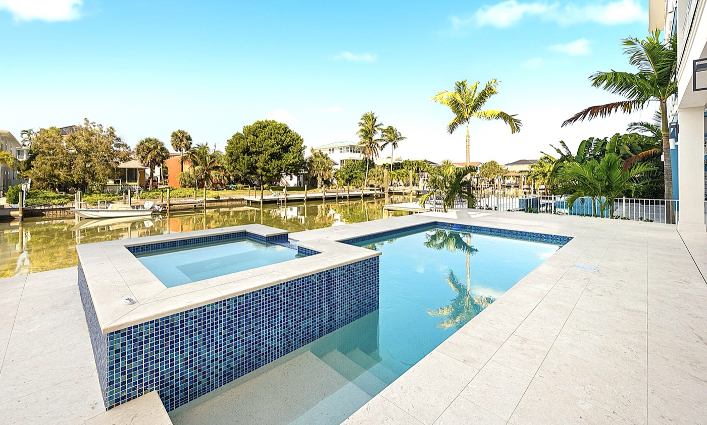 Waterfront geometric pool and raised spa in glass mosaic tile with travertine deck and boat dock — Coastal Residence